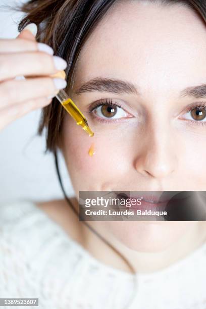 apply drop of oil on face for skin care. cosmetics and beauty concept - natuurlijke staat stockfoto's en -beelden