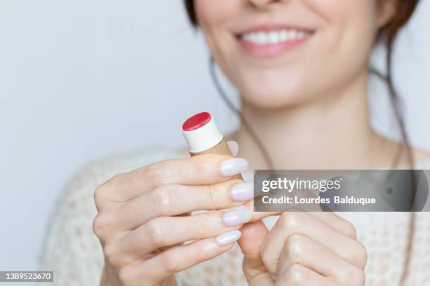 close-up of woman holding lipstick with cardboard box - sustainable cosmetics stock pictures, royalty-free photos & images