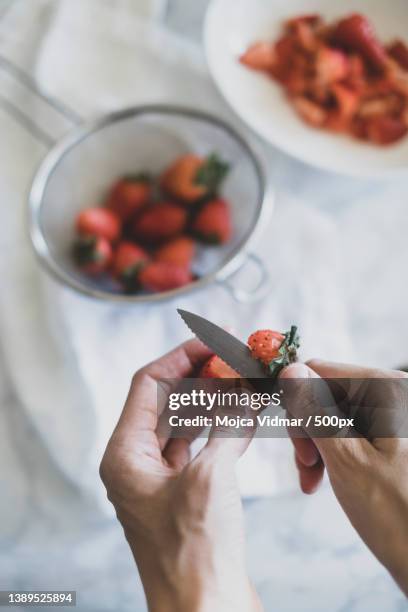 homemade strawberry cake,cropped hands of person cutting strawberries on table - fruit bowl stock pictures, royalty-free photos & images