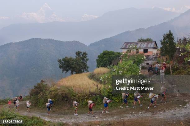 Young Nepalese men take part in a doko race during one of the many strenuous physical exams administered during the British Gurkha tryouts in...