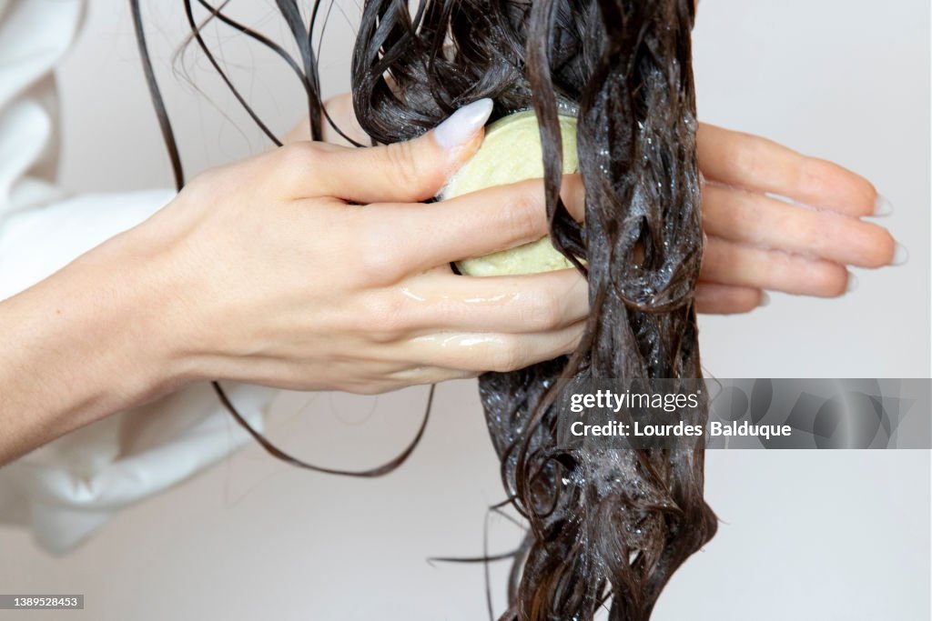 Woman using solid soap washing hair with shampoo bar