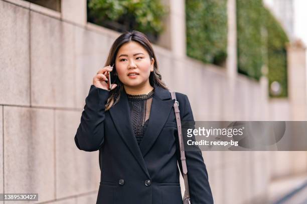 電話で話しながら通勤するビジネスウーマン - buxom women ストックフォトと画像