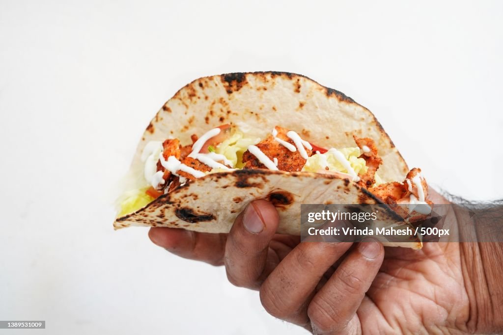 Male hand holding fish Tacos against white background,Selective focus