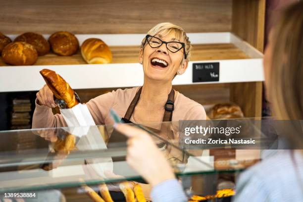 ältere frau in der bäckerei, die gebäck serviert - verkäuferin stock-fotos und bilder