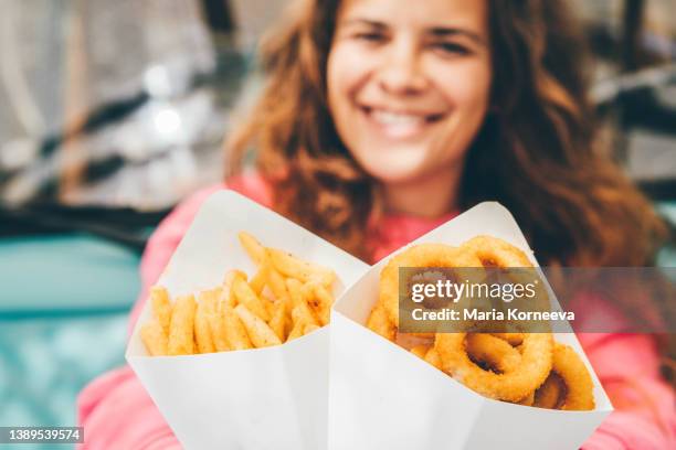 smiling woman holding fried onion rings and french fries. - cholesterol stockfoto's en -beelden