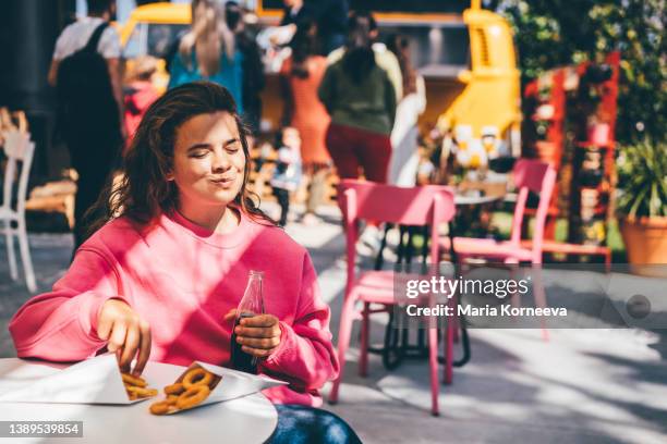 smiling woman eating fried onion rings. - cholesterol stock pictures, royalty-free photos & images