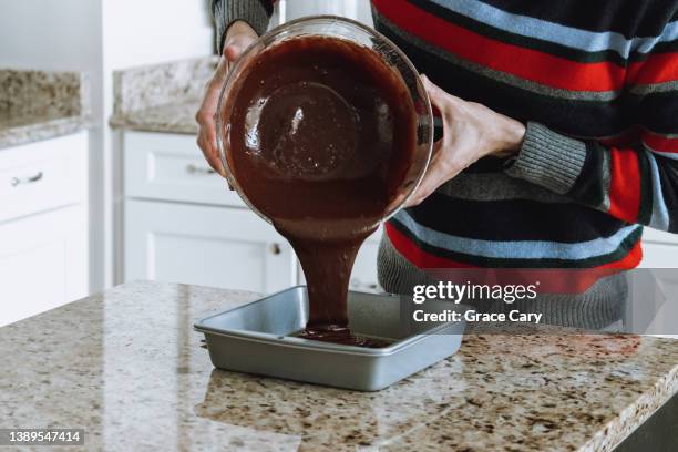 man pours chocolate batter into baking pan - ausbackteig stock-fotos und bilder