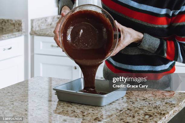 man pours chocolate batter into baking pan - forma de bolo imagens e fotografias de stock