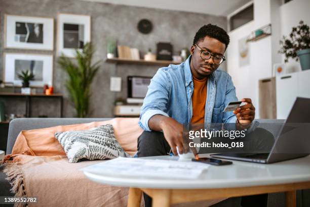 man using paying bank card for paying online - home finances man stock pictures, royalty-free photos & images