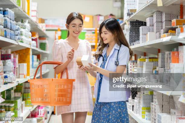 asian female pharmacist explaining the medicinal properties on the pillbox to a patient or customer according to the doctor's prescription and providing customers with e-service payment at the custome - drug ストックフォトと画像