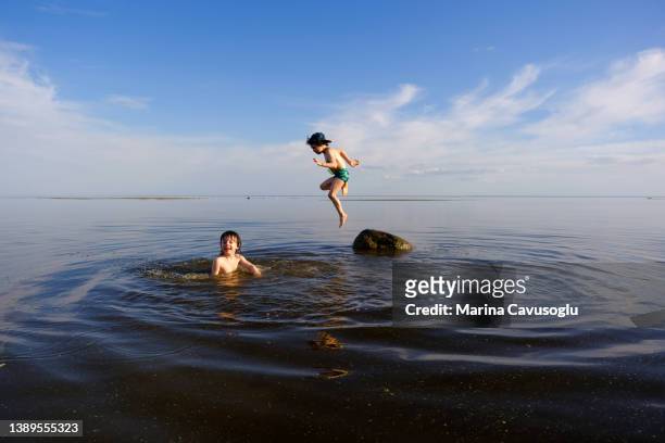wild swimming in a local lake. family boys having fun in water. - holiday blue sky stock pictures, royalty-free photos & images
