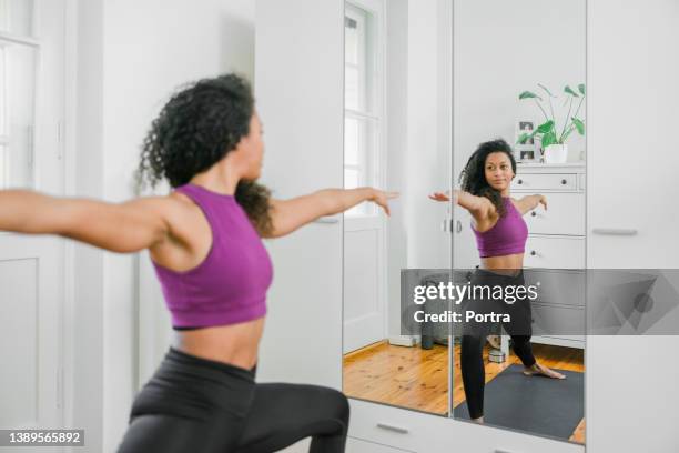 fitte junge frau, die yoga vor einem spiegel macht - exercise room stock-fotos und bilder