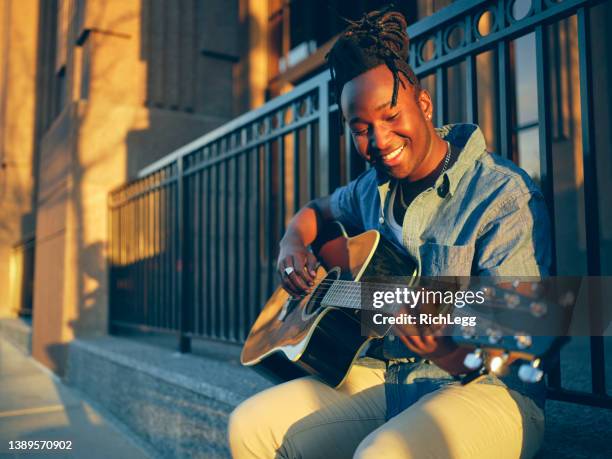 young man playing guitar in the city - busker 個照片及圖片檔