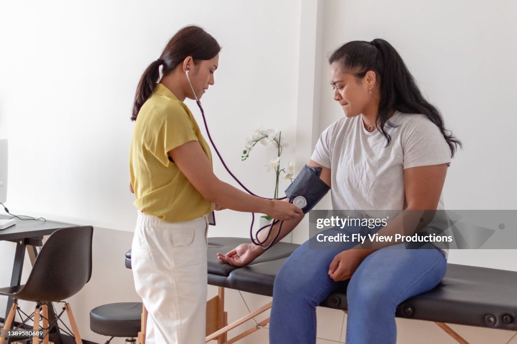 Woman having blood pressure measured by doctor