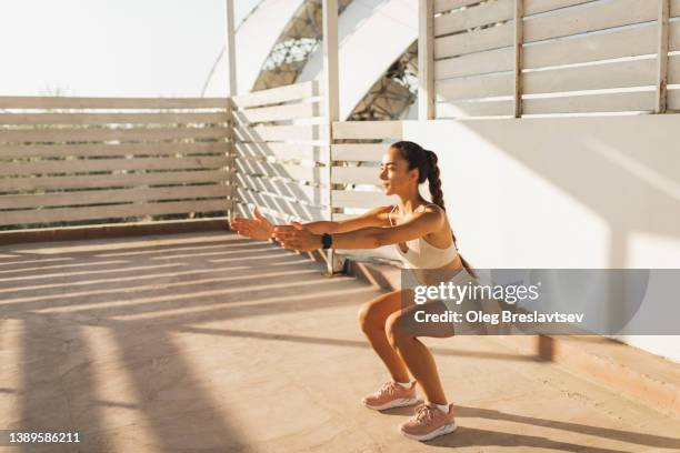 woman doing squats, interval endurance workout outdoors. effort and concentration. female power - hurken stockfoto's en -beelden