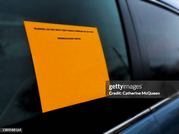 wheel clamp: bright orange immobilization notice sticker on parked car - department of motor vehicles stock pictures, royalty-free photos & images