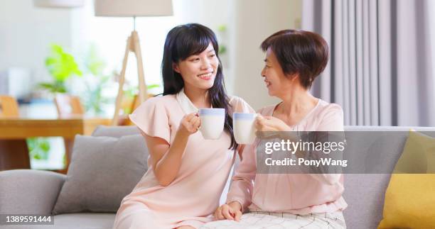mama und töchter trinken zusammen - family on couch with mugs stock-fotos und bilder