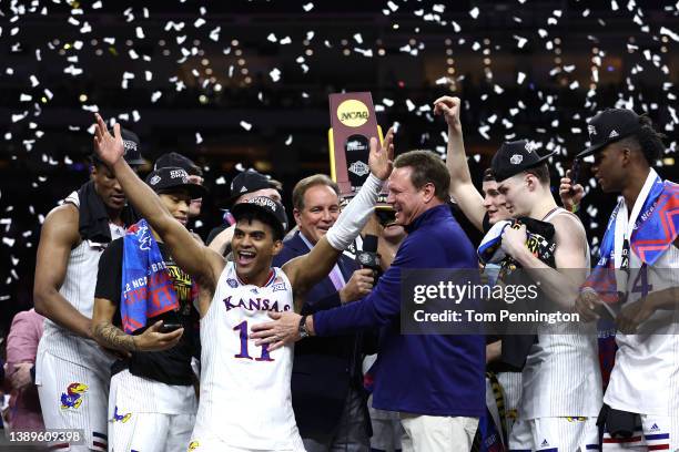 Remy Martin of the Kansas Jayhawks reacts as Kansas Jayhawks players and coaches hold up the trophy after defeating the North Carolina Tar Heels...