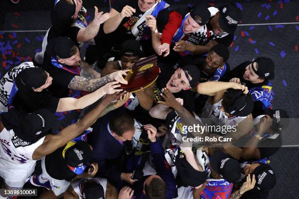 Kansas Jayhawks players and coaches hold up the trophy after defeating the North Carolina Tar Heels 72-69 during the 2022 NCAA Men's Basketball...