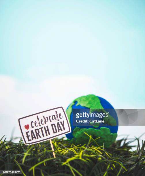 handgefertigter globus in gras mit schild zum tag der erde. rette den planeten - earth day stock-fotos und bilder