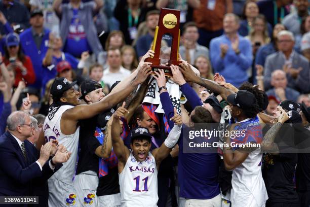 Remy Martin of the Kansas Jayhawks reacts as Kansas Jayhawks players and coaches hold up the trophy after defeating the North Carolina Tar Heels...