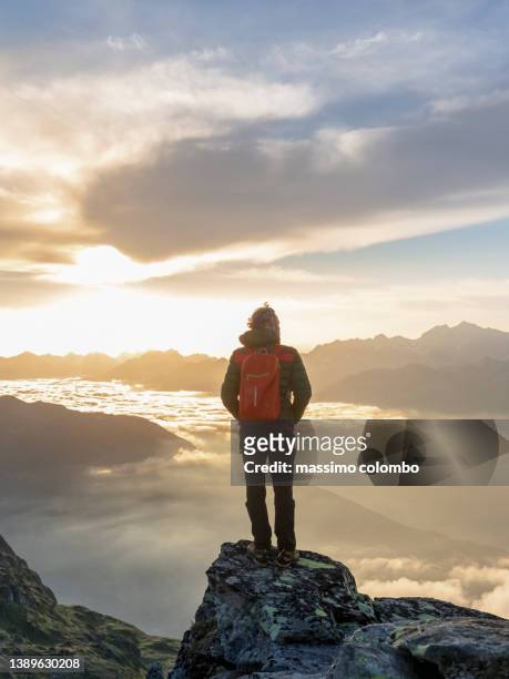 hiker with backpack standing on mountain against sky during wonderful sunset - travel stock-fotos und bilder