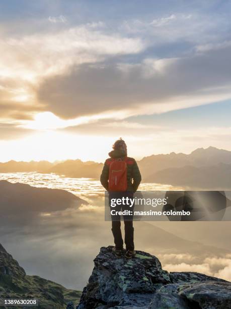 hiker with backpack standing on mountain against sky during wonderful sunset - traveling stock pictures, royalty-free photos & images