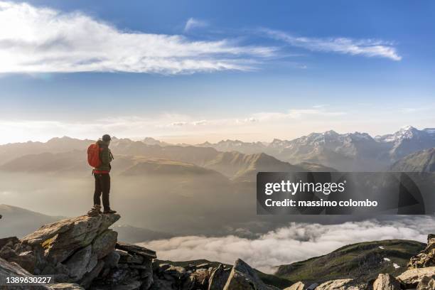 alpinist  on the peak of a mountain looking panorama valley - on top of stock pictures, royalty-free photos & images