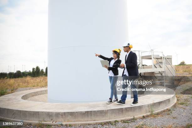 junge ingenieure diskutieren über windturbinenprojekt im windturbinenpark, green engergy business discussion - natuurkunde stock-fotos und bilder