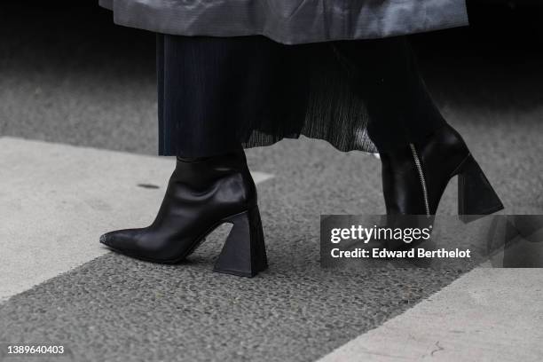 Guest wears a black long dress, black shiny leather pointed / block asymmetric heels ankle boots , outside Gauchere, during Paris Fashion Week -...