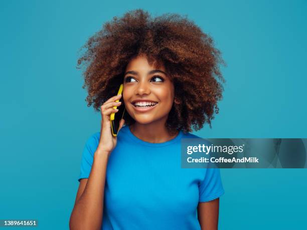 beautiful smiling girl with curly hairstyle using smart phone - curly girl stock pictures, royalty-free photos & images