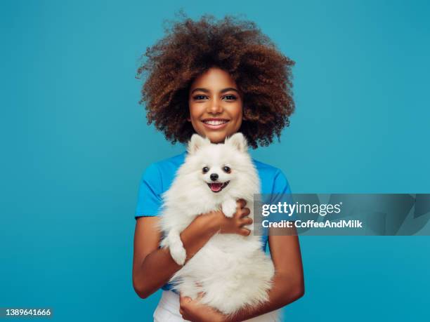 retrato de estudio de una joven afroamericana sonriente sosteniendo a un perrito - pet owner fotografías e imágenes de stock