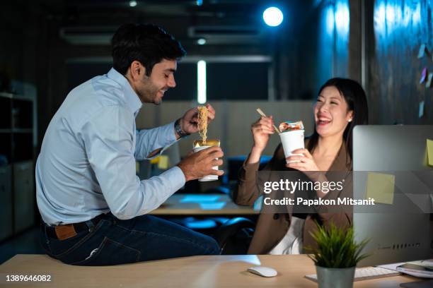 two asian businessmen eating instant noodles after having a hard time having fun. - nouilles photos et images de collection