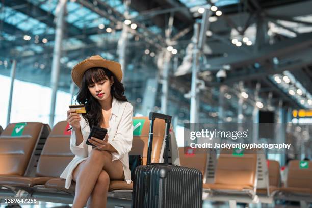 young asian traveler woman entering credit pin on the smartphone in the airport terminal - travel credit card stock pictures, royalty-free photos & images