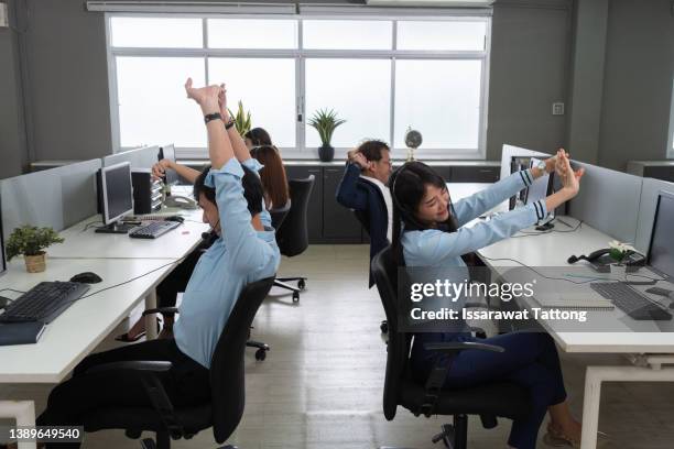 office relax concept. employee stretching with hands behind her head in ergonomic office chair after long hours working at laptop with mock up screen, take break, do simple exercises sitting at workplace - stretching at work stock pictures, royalty-free photos & images