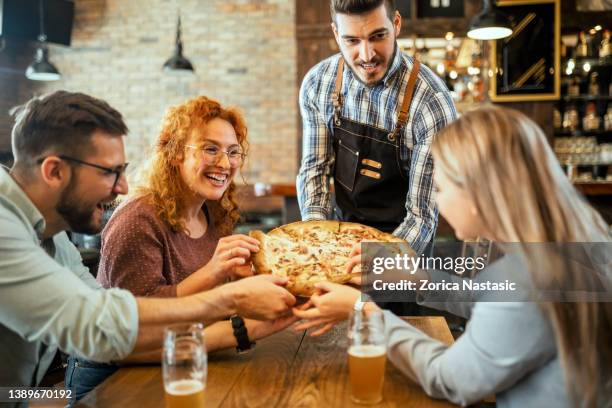 waiter serving pizza to a group of friends - pizza restaurant stock pictures, royalty-free photos & images