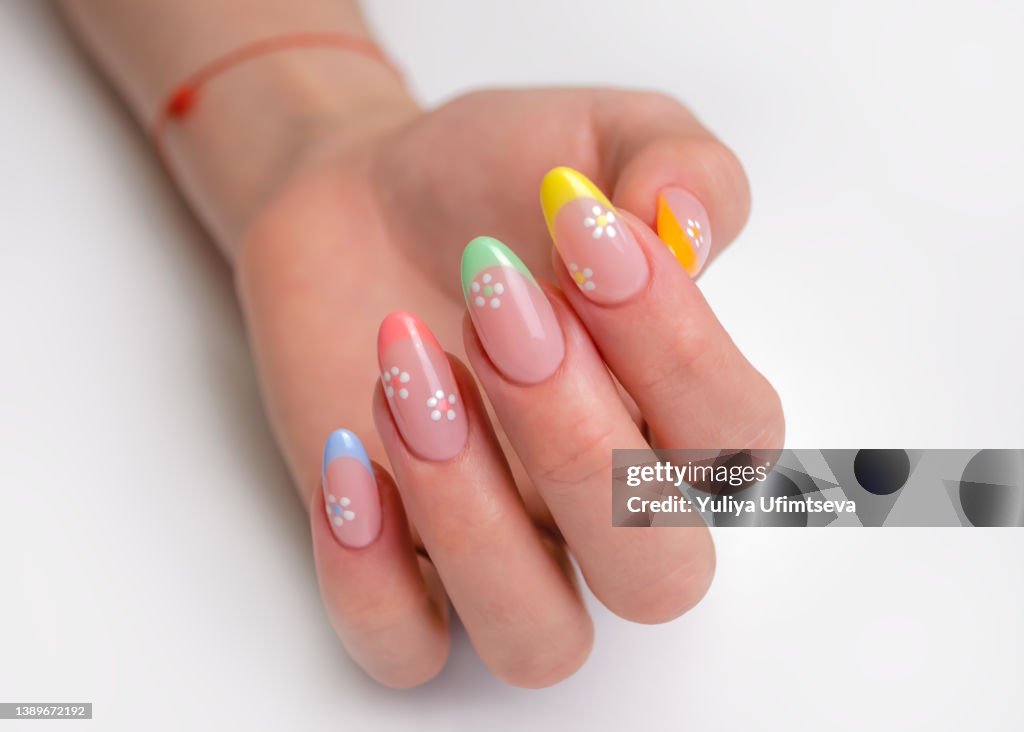 Hands of a young woman with a manicure. The nails are covered with gel polish with colored French and flowers