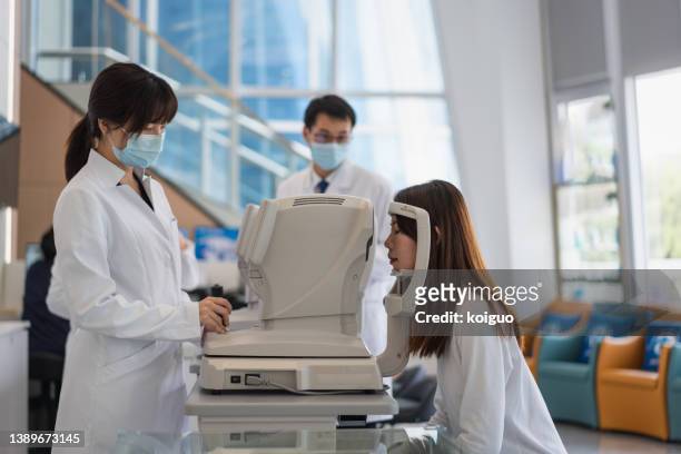 ophthalmologist and nurse examining female patient's eyes using modern instruments - phoroptor stock pictures, royalty-free photos & images