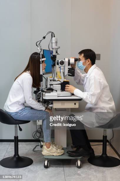 asian male doctor examining patient's eyes - optical equipment stock pictures, royalty-free photos & images