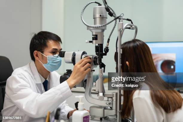 asian male doctor examining patient's eyes - réfracteur photos et images de collection