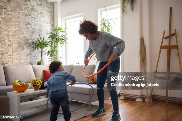 mother and son playing with hula hoop in the living room - hooping stock pictures, royalty-free photos & images