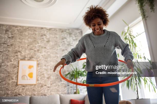 woman black ethnicity spinning the hula hoop around her waist - hoelahoep stockfoto's en -beelden