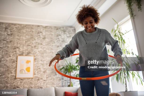woman black ethnicity spinning the hula hoop around her waist - jogar ao arco imagens e fotografias de stock