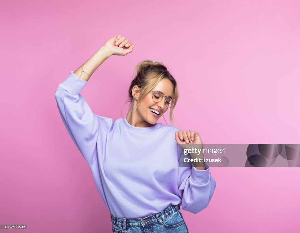 Mujer feliz bailando sobre fondo rosa
