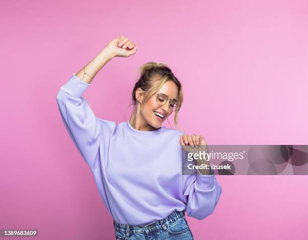 mujer feliz bailando sobre fondo rosa - physical position fotografías e imágenes de stock
