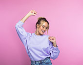 Happy woman dancing against pink background