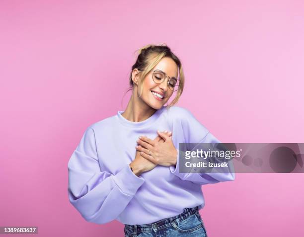 happy woman keeping hands on heart - woman heart stock pictures, royalty-free photos & images