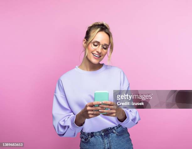 happy woman using smart phone - colored background stockfoto's en -beelden