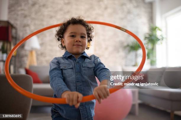 toddler boy, playing with a hula hoop in the living room - hooping stock pictures, royalty-free photos & images