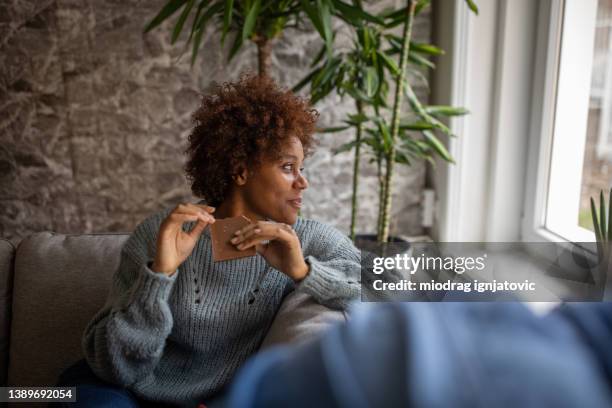 madre sentada en el sofá con su hijo y comiendo chocolate - chocolate fotografías e imágenes de stock